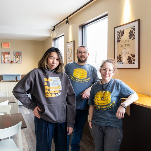 Three Bao & Beyond staff members, two women and one man, pose inside the restaurant.